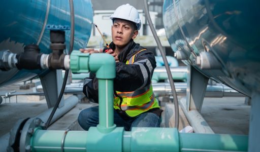 Focused industrial engineer using a calibration tool to check equipment at a manufacturing plant, ensuring operational efficiency.